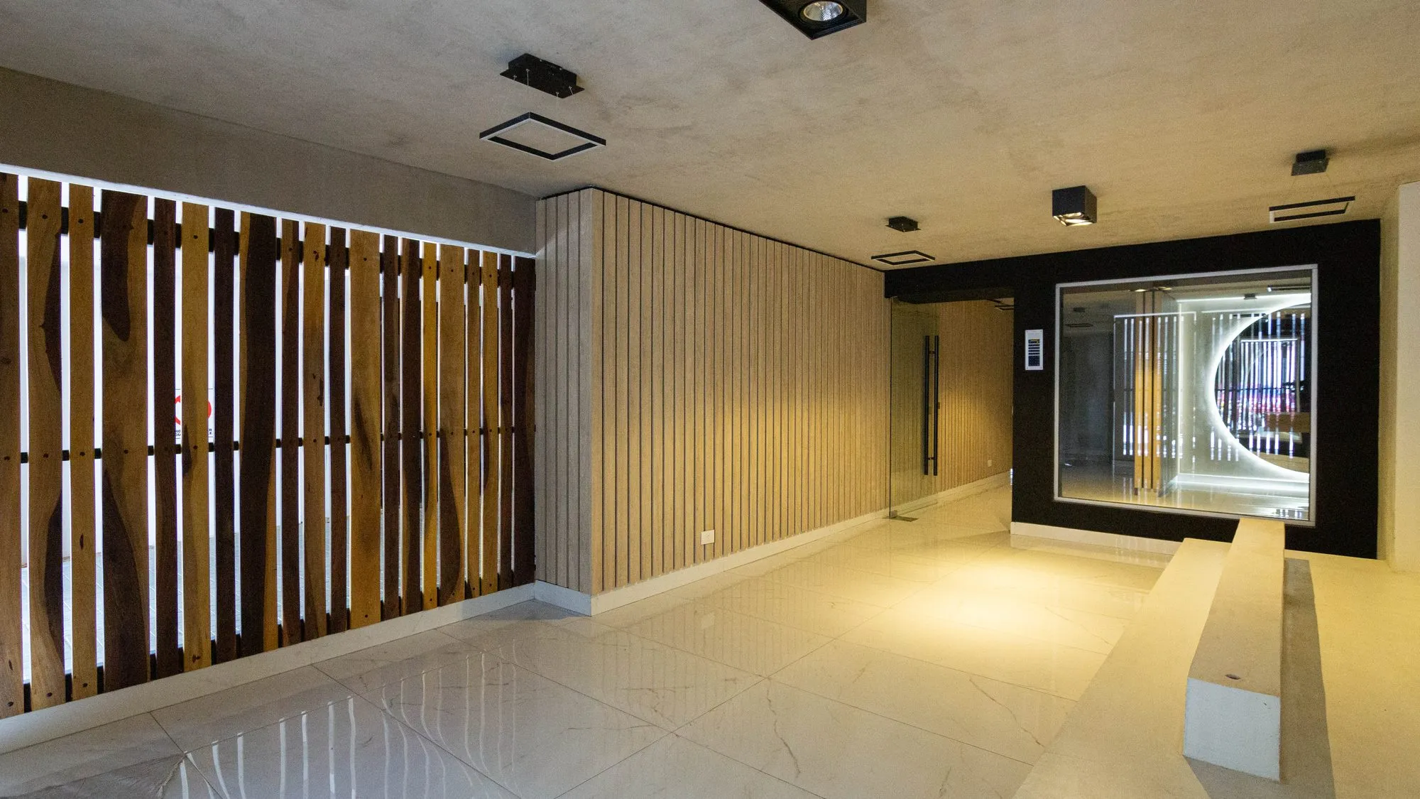 Hall de acceso con madera natural en listones e iluminación embutida